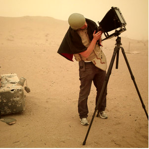 Richard Mosse, wearing helmet and bulletproof vest while using a large format camera in Iraq. The camera is similar to the one he would use later in the Congo.